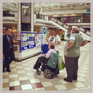 Citizens Advice staff running a scam awareness stall at Middleton Grange Shopping Centre to educate the public